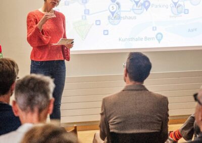 Eva Schmassmann, Plattform Agenda 2030 präsentiert den SDG Walk. Auf Leinwand sieht man die Route und Stationen.