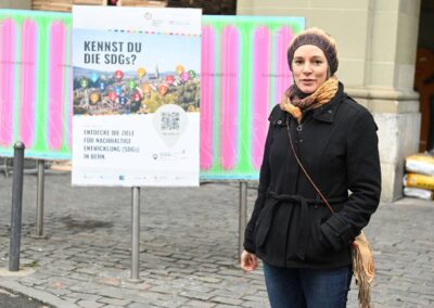 Eva Schmassmann, Plattform Agenda 2030, vor Plakat des SDG Walk, spricht Richtung Kamera
