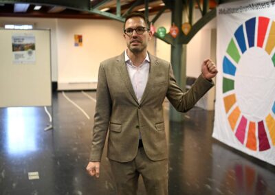 Felix Hüppi, Direktor Kornhausbibliotheken. Im Hintergrund grosse Leinwand mit SDG-Rad.