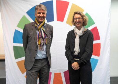 Vor grosser Leinwand mit SDG-Rad stehen Alec von Graffenried und Tatjana von Steiger