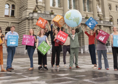 Eine Gruppe von Menschen steht mit grossen SDG-Würfeln und einer grossen Weltkugel auf dem Bundesplatz.