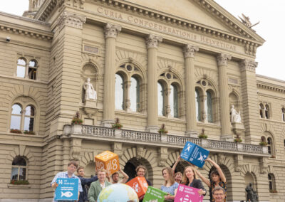 Eine Gruppe von Menschen steht mit grossen SDG-Würfeln und einer grossen Weltkugel auf dem Bundesplatz.